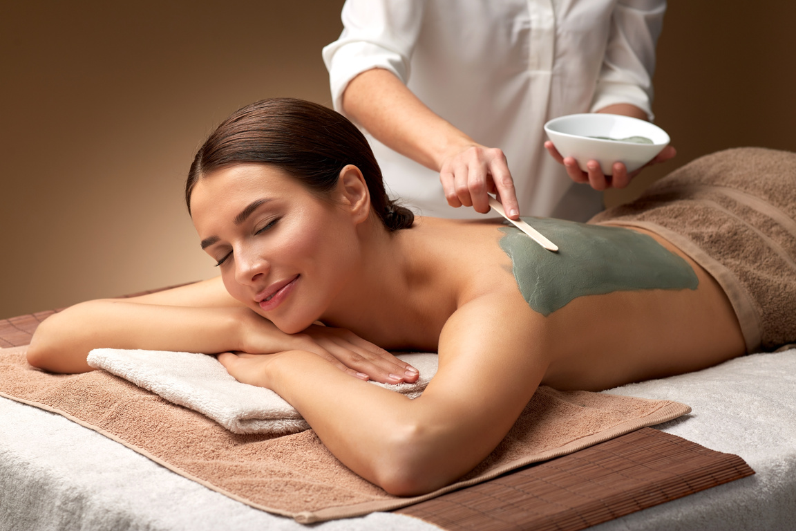 Cosmetologist Applying Clay Mask on a Woman's Back